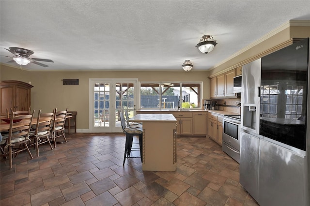 kitchen with a sink, ornamental molding, light countertops, stainless steel appliances, and a kitchen breakfast bar