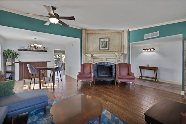 living room featuring visible vents, wood finished floors, a fireplace, and crown molding