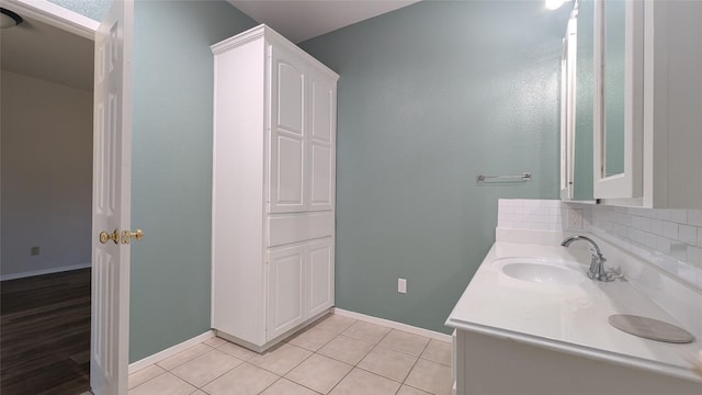 bathroom featuring tile patterned flooring, vanity, baseboards, and backsplash