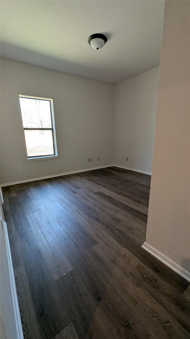 unfurnished room featuring baseboards and dark wood-style flooring