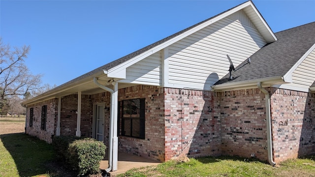 view of home's exterior with brick siding and a shingled roof