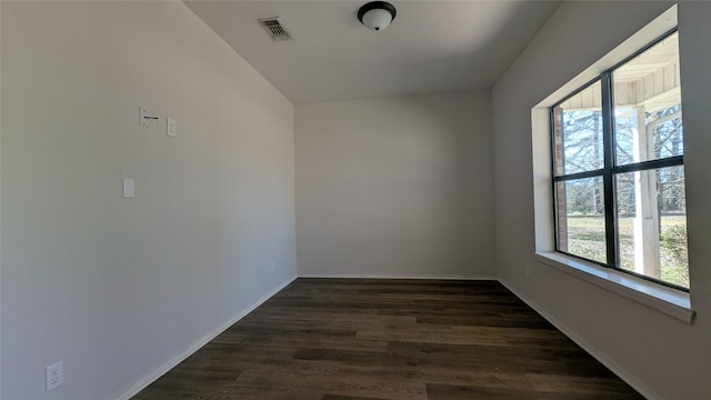 empty room with visible vents, baseboards, and dark wood-style floors