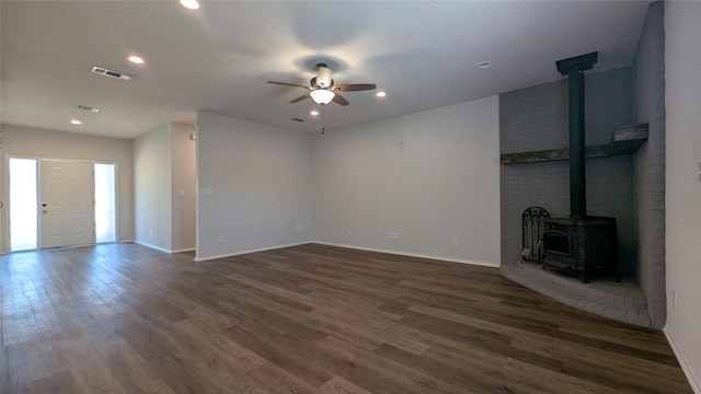 unfurnished living room with a wood stove, a ceiling fan, recessed lighting, baseboards, and dark wood-style flooring