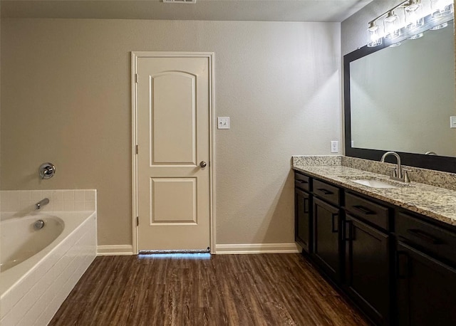 full bathroom featuring vanity, wood finished floors, visible vents, baseboards, and a bath