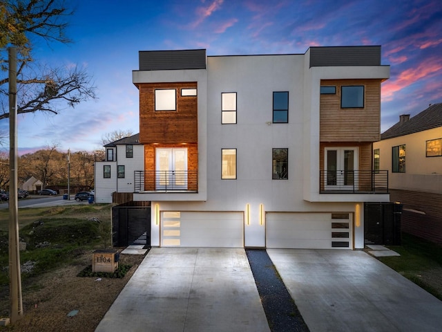 contemporary house with concrete driveway, a balcony, and stucco siding