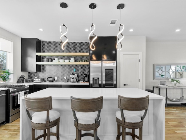 kitchen featuring open shelves, light countertops, light wood-type flooring, and appliances with stainless steel finishes