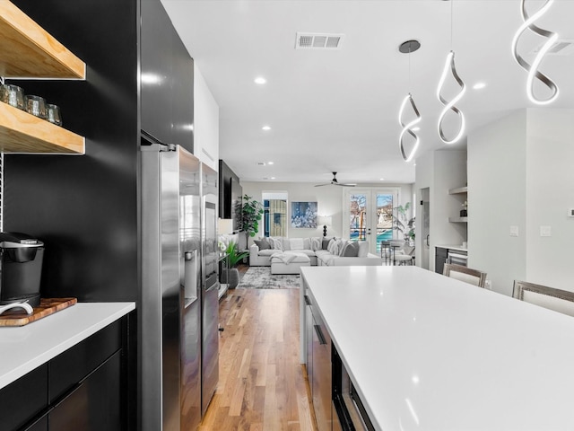 kitchen featuring visible vents, french doors, light wood-style floors, light countertops, and dark cabinets