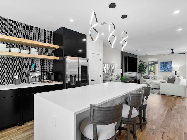 kitchen with visible vents, stainless steel fridge with ice dispenser, dark cabinets, and open shelves