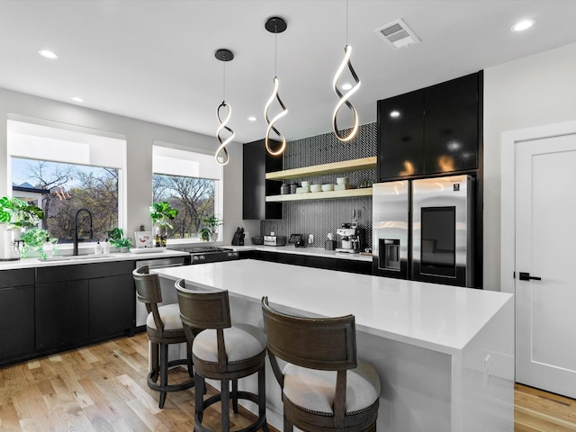 kitchen with appliances with stainless steel finishes, dark cabinetry, and a sink