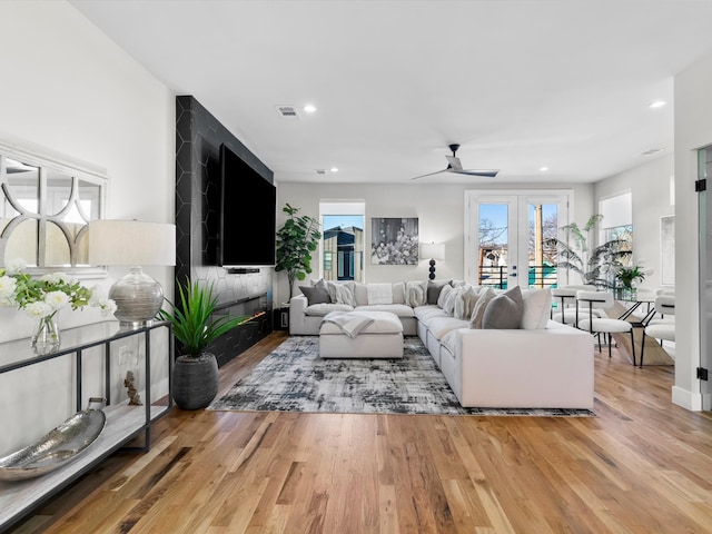 living room featuring visible vents, recessed lighting, a fireplace, french doors, and wood finished floors