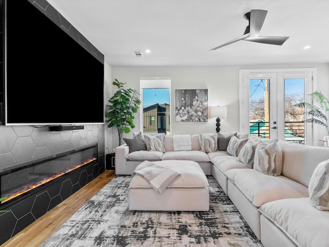 living room with wood finished floors, visible vents, a ceiling fan, recessed lighting, and a glass covered fireplace