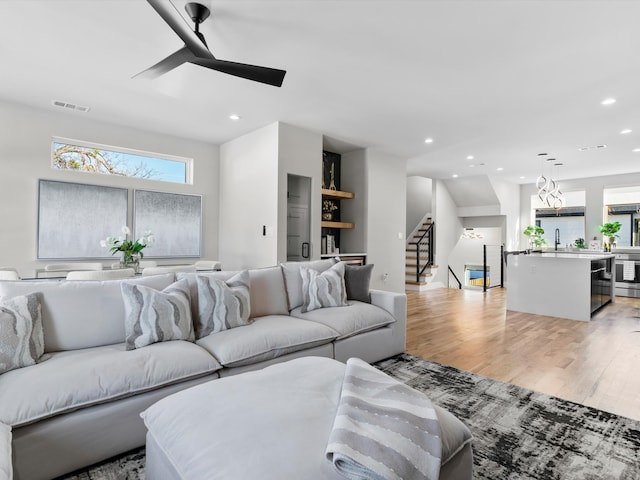 living room with light wood finished floors, visible vents, recessed lighting, and stairway