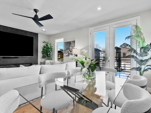 living room with wood finished floors, a ceiling fan, recessed lighting, french doors, and an accent wall