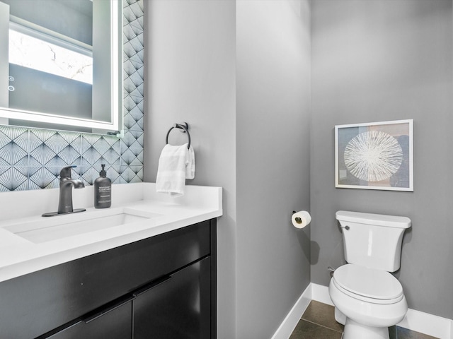 half bathroom featuring tile patterned floors, toilet, backsplash, baseboards, and vanity