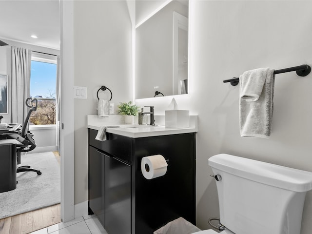 half bath with baseboards, toilet, and vanity