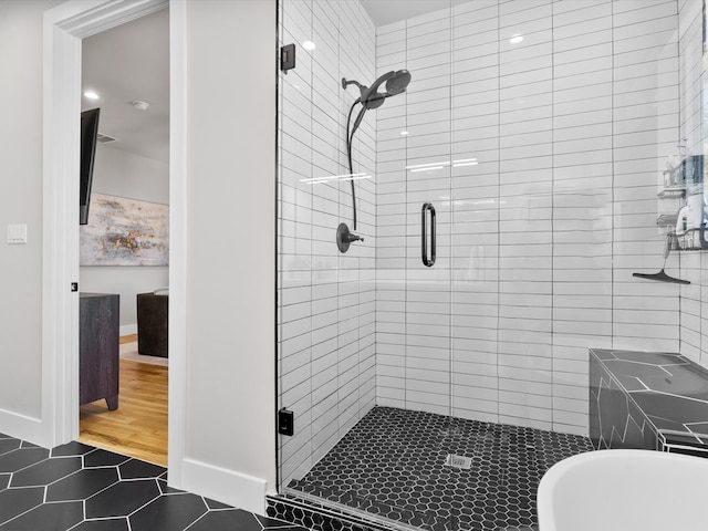 bathroom with a shower stall, baseboards, tile patterned floors, and a freestanding bath