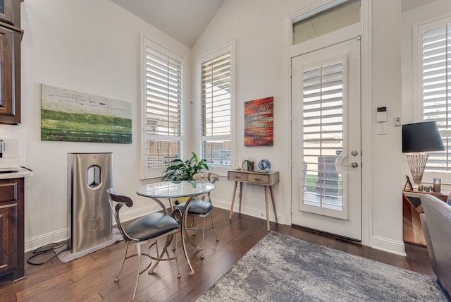 dining area featuring dark wood-type flooring, baseboards, and vaulted ceiling