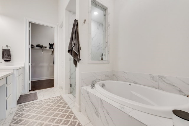 full bath with a marble finish shower, a walk in closet, a garden tub, marble finish floor, and vanity