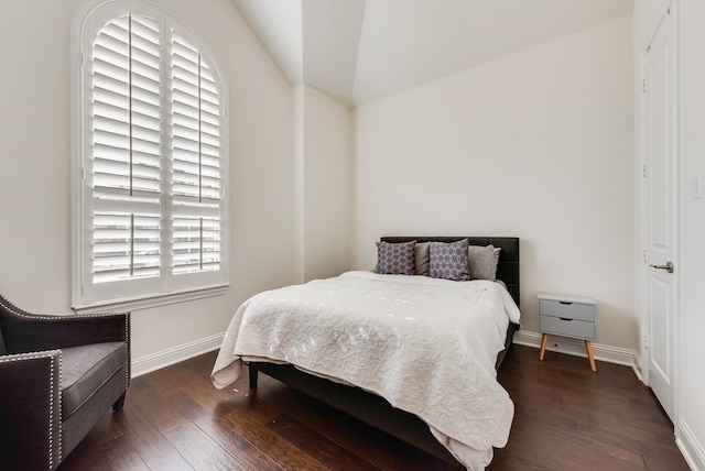 bedroom featuring dark wood-type flooring, baseboards, and vaulted ceiling