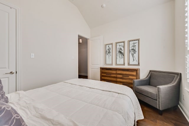 bedroom with dark wood-style floors, baseboards, and vaulted ceiling