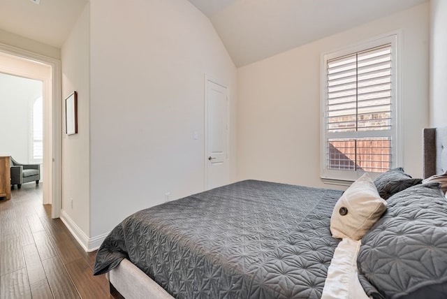 bedroom featuring vaulted ceiling, wood finished floors, and baseboards