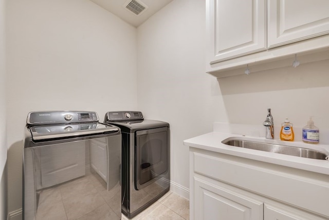 laundry area with light tile patterned floors, visible vents, cabinet space, a sink, and washing machine and dryer