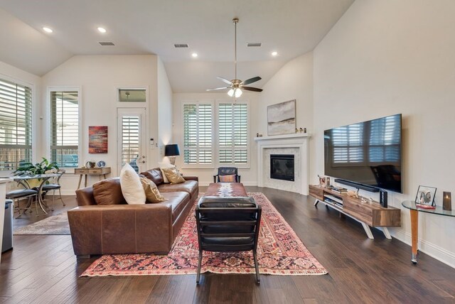 living room featuring visible vents, a glass covered fireplace, dark wood-style flooring, and vaulted ceiling