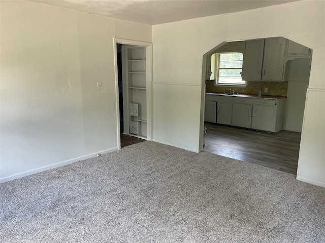 interior space featuring a sink, baseboards, and dark carpet