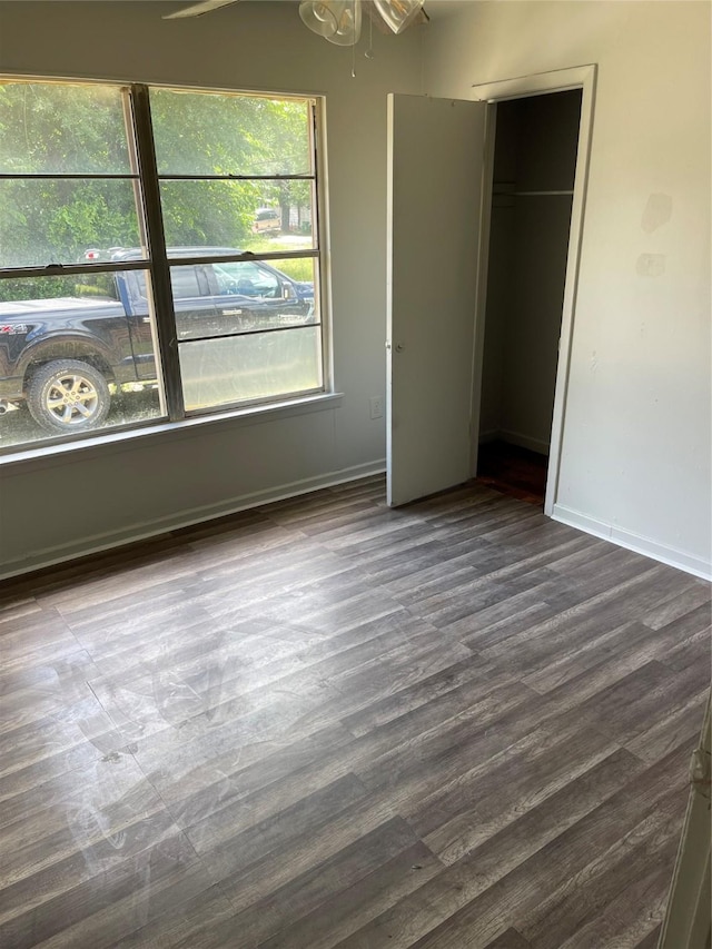 unfurnished bedroom featuring baseboards and dark wood-style flooring