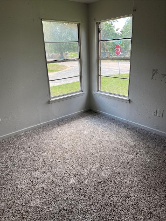 empty room with a textured wall, baseboards, and carpet floors