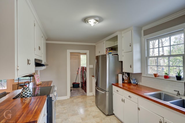 kitchen featuring butcher block countertops, ornamental molding, washing machine and dryer, appliances with stainless steel finishes, and decorative backsplash