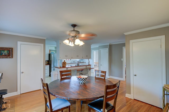 dining room with crown molding, light wood-style floors, baseboards, and ceiling fan