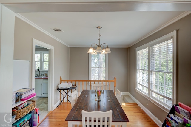 dining space featuring plenty of natural light, light wood-style floors, an inviting chandelier, and crown molding