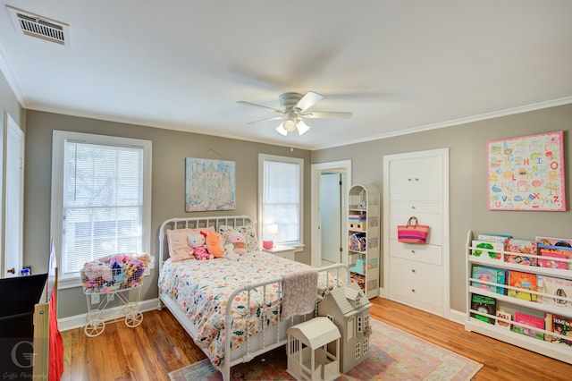 bedroom with visible vents, ornamental molding, a ceiling fan, wood finished floors, and baseboards