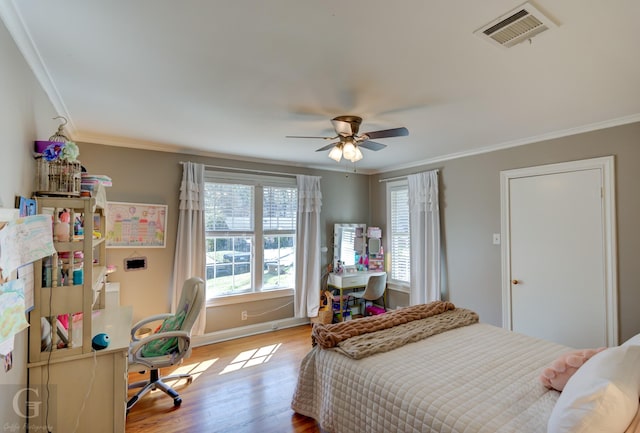 bedroom featuring crown molding, wood finished floors, visible vents, and ceiling fan