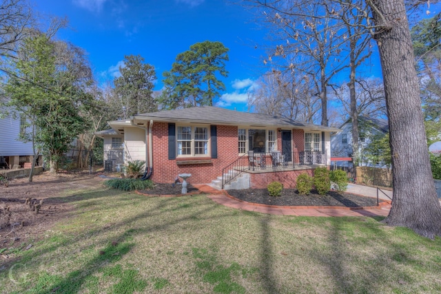 view of front facade featuring brick siding, a front yard, and fence