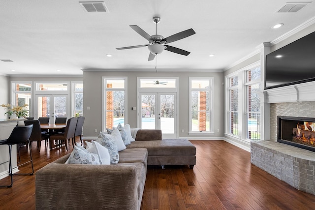 living room with dark wood finished floors, a brick fireplace, french doors, and visible vents