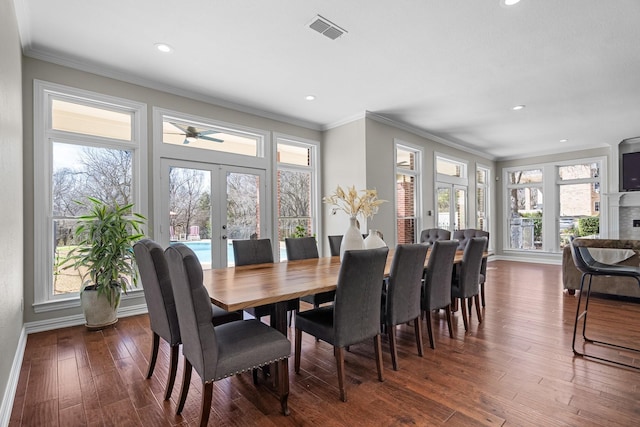 dining area with dark wood-style floors, visible vents, a fireplace, ornamental molding, and french doors