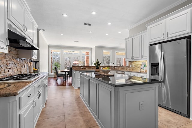 kitchen featuring light tile patterned floors, visible vents, stainless steel appliances, under cabinet range hood, and crown molding