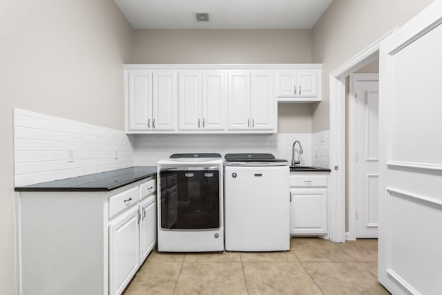 clothes washing area featuring light tile patterned floors, visible vents, washing machine and clothes dryer, cabinet space, and a sink