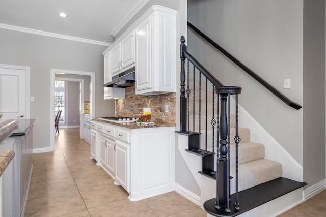 kitchen featuring tasteful backsplash, white gas cooktop, under cabinet range hood, ornamental molding, and white cabinetry