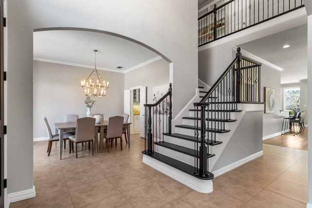 stairway with baseboards, arched walkways, ornamental molding, and tile patterned flooring