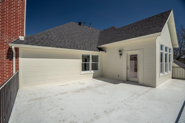 rear view of property featuring brick siding, a patio, and roof with shingles