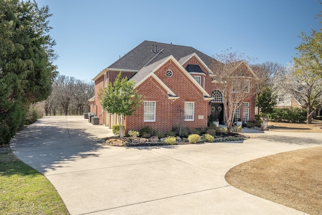 view of front of property featuring brick siding, concrete driveway, and a shingled roof