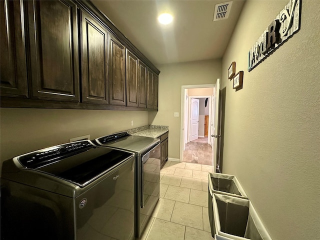 clothes washing area featuring light tile patterned floors, baseboards, visible vents, cabinet space, and washer and clothes dryer