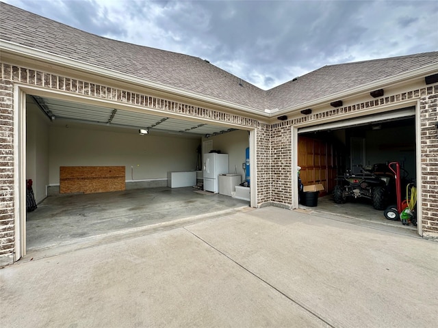 garage featuring concrete driveway and freestanding refrigerator