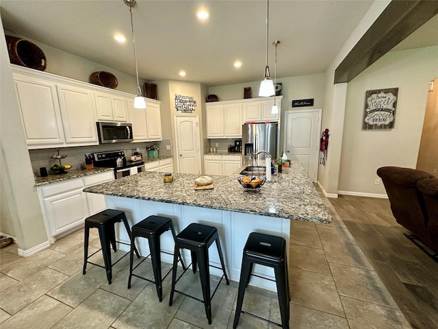 kitchen featuring white cabinetry, a breakfast bar area, a large island with sink, and stainless steel appliances