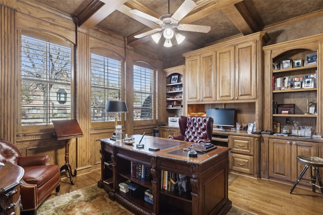 office area featuring built in features, light wood-type flooring, beam ceiling, coffered ceiling, and a ceiling fan