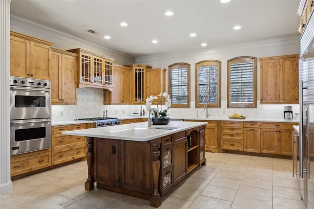 kitchen with visible vents, a sink, light countertops, stainless steel appliances, and a kitchen island with sink