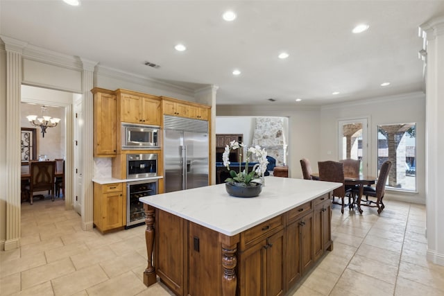 kitchen with a center island, crown molding, wine cooler, built in appliances, and light countertops